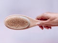 Brush with a handle for dry anti-cellulite massage or brushing in the hand of a girl in soft pink colors.  Beauty concept Royalty Free Stock Photo