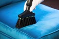 a brush head cleaning a velvety blue upholstered chair