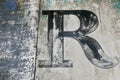 Brush lettered capital R on grungy metal surface