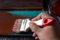 Brush with paint in hand. A man paints blue boards in a brown paint brush. Royalty Free Stock Photo