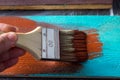 Brush with paint in hand. A man paints blue boards in a brown paint brush. Royalty Free Stock Photo