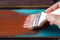 Brush with paint in hand. A man paints blue boards in a brown paint brush. Royalty Free Stock Photo