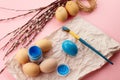 brush with paints and eggs, coloring Easter eggs in blue on a pink pastel background Royalty Free Stock Photo