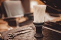 Brush for shaving beard along with bowl, blurred background of hair salon for men, barber shop Royalty Free Stock Photo