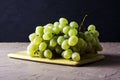 a brush of table white grapes on a cutting board on a dark background Royalty Free Stock Photo