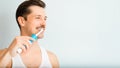 Brush teeth, oral hygiene, whitening banner with copy space for text. Side view of handsome man with toothy smile brushing teeth Royalty Free Stock Photo