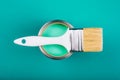 Brush on open can with turquoise color of paint on blue background. Royalty Free Stock Photo