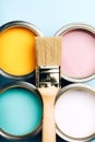 Brush with wooden handle on open cans on blue pastel background. Royalty Free Stock Photo