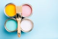 Brush with wooden handle on open cans on blue pastel background. Royalty Free Stock Photo