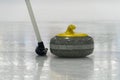 Brush and yellow Curling stone on the ice Royalty Free Stock Photo