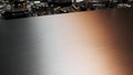Brushed metallic surface with warm copper and cool silver gradient, reflecting blurred electronic components Royalty Free Stock Photo
