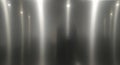 Brushed stainless steel surface displaying vertical streaks of light reflection. The texture is Royalty Free Stock Photo
