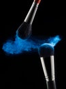Brushes for a make-up on a black background with blue powder splash close up. Cosmetics, style, fashion Royalty Free Stock Photo
