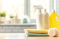 Cleaning products on wooden table against blurred modern kitchen interior background