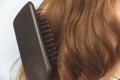 Brushing beautiful light auburn hair of an anonymous woman. Hairstyling concept. Studio shot