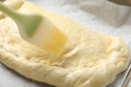 Brushing egg yolk onto uncooked calzone pizza, closeup Royalty Free Stock Photo