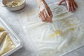 Hand brushing a filo pastry sheet with melted butter on the table