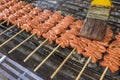 Brushing marinade on skewered Chicken small intestine, or locally known in the Philippines as isaw, on a charcoal grill