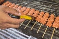 Brushing marinade on skewered Chicken small intestine, or locally known in the Philippines as isaw, on a charcoal grill