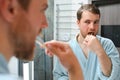 Brushing teeth in the morning. Rear view of handsome young beard man brushing his teeth and smiling while standing Royalty Free Stock Photo