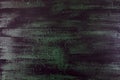 Brushstrokes with thick paint in shades of green, blue, purple on old wooden texture