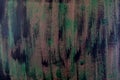 Brushstrokes with thick paint in shades of green, blue, purple on old wooden texture