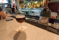 Craft beer in old stylish glass on bar counter of restaurant with visitors and bartenders