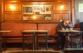 Older man alone writing letter inside old bar of cafe with historical interior and evening light