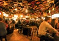 Visitors of huge bar drinking and talking in lights of vintage beer restaurant