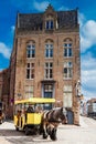 People touring around the beautiful Bruges town on a carriage pulled by a horse