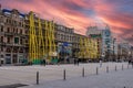 A Brussels cityscape with several buildings in a renovation process against a vibrant evening sky