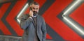 brutal adult male businessman speaks on a mobile phone against the background of a bright wall with red arrows