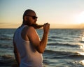 A brutal bald man posing on the beach at sunset in his underwear and touching his red beard. A parody of a glamorous Royalty Free Stock Photo