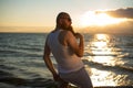 A brutal bald man posing on the beach at sunset in his underwear and touching his red beard. A parody of a glamorous Royalty Free Stock Photo