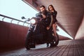 Brutal bearded biker in black leather jacket and sensual brunette girl sitting together on a custom-made retro Royalty Free Stock Photo