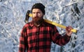 Brutal bearded lumberjack with ax in winter forest. Lumberjack with an ax in his hands. Male holds an ax on a shoulder