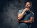 A man with tattooed arms over dark grey background. Royalty Free Stock Photo