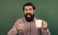 brutal bearded man hold cup of tea and show thumb up. morning energy. just inspired. back to school. formal education