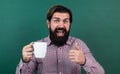 brutal bearded man hold cup of tea and show thumb up. morning energy. just inspired. back to school. formal education