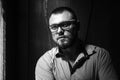 Brutal bearded man with a tattoo on his arm, portrait of a man in dramatic light against a brown wooden wall, bearded male with