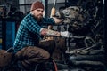 Mechanicl inspecting engine of a car in a garage.