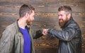Brutal bearded men wear leather jackets shaking hands. Strong handshake. Friendship of brutal guys. Approved business