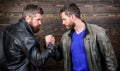 Brutal bearded men wear leather jackets shaking hands. Strong handshake. Friendship of brutal guys. Handshake symbol of