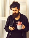 Brutal caucasian hipster holding cup or mug and cell phone