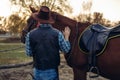 Brutal cowboy poses with horse, wild west