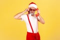 Brutal grey bearded adult man in santa claus hat holding handset of landline telephone and looking at camera through sunglasses, Royalty Free Stock Photo