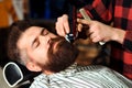 Brutal guy sitting in barber chair. Vintage barbershop, business. Beard styling and cut