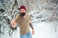 Brutal hipster with beard and tattooe holding axe outdoors in winter