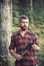 Brutal lumberjack in woods. Bearded guy holding small spade in his hands. Young scientist doing research in wilderness