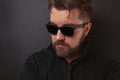 A brutal man with a beard and a stylish hairdo in a black suit and sunglasses Royalty Free Stock Photo